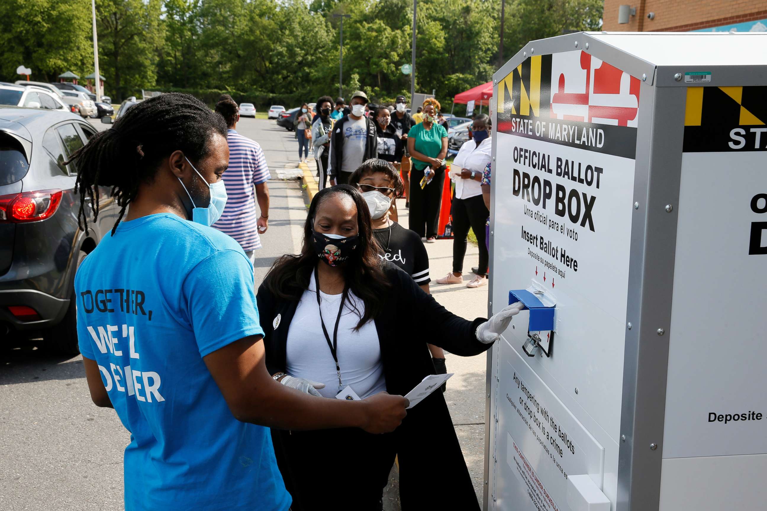 PHOTO: Maryland election judge Cassandra Campbell helps a voter wearing a face mask to prevent the spread of coronavirus disease casts his ballot in the Maryland presidential primary election in College Park, Maryland, June 2, 2020. 