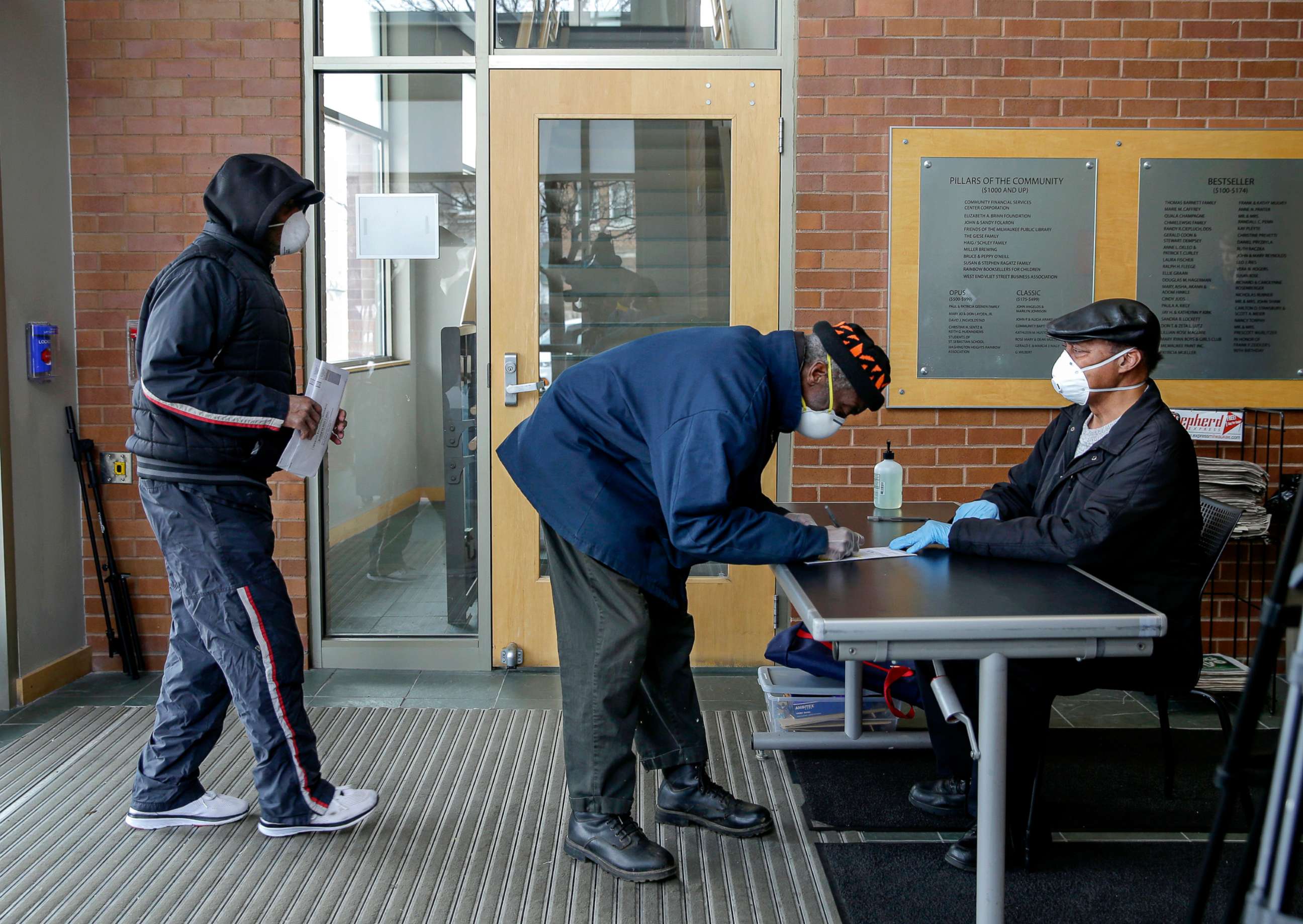 PHOTO: Voters come to drop their ballots with face masks, April 4, 2020, at the Washington Park Library in Milwaukee.