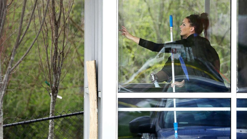 A worker vacuums debris from shattered glass as another worker cleans windows inside a Waffle House restaurant Monday, April 23, 2018, in Nashville, Tenn.