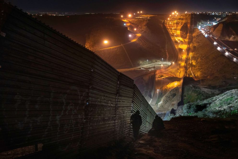 PHOTO: Migrants looks for a place to jump the border fence to get into the U.S. , from Tijuana, Mexico, Dec. 29, 2018. 