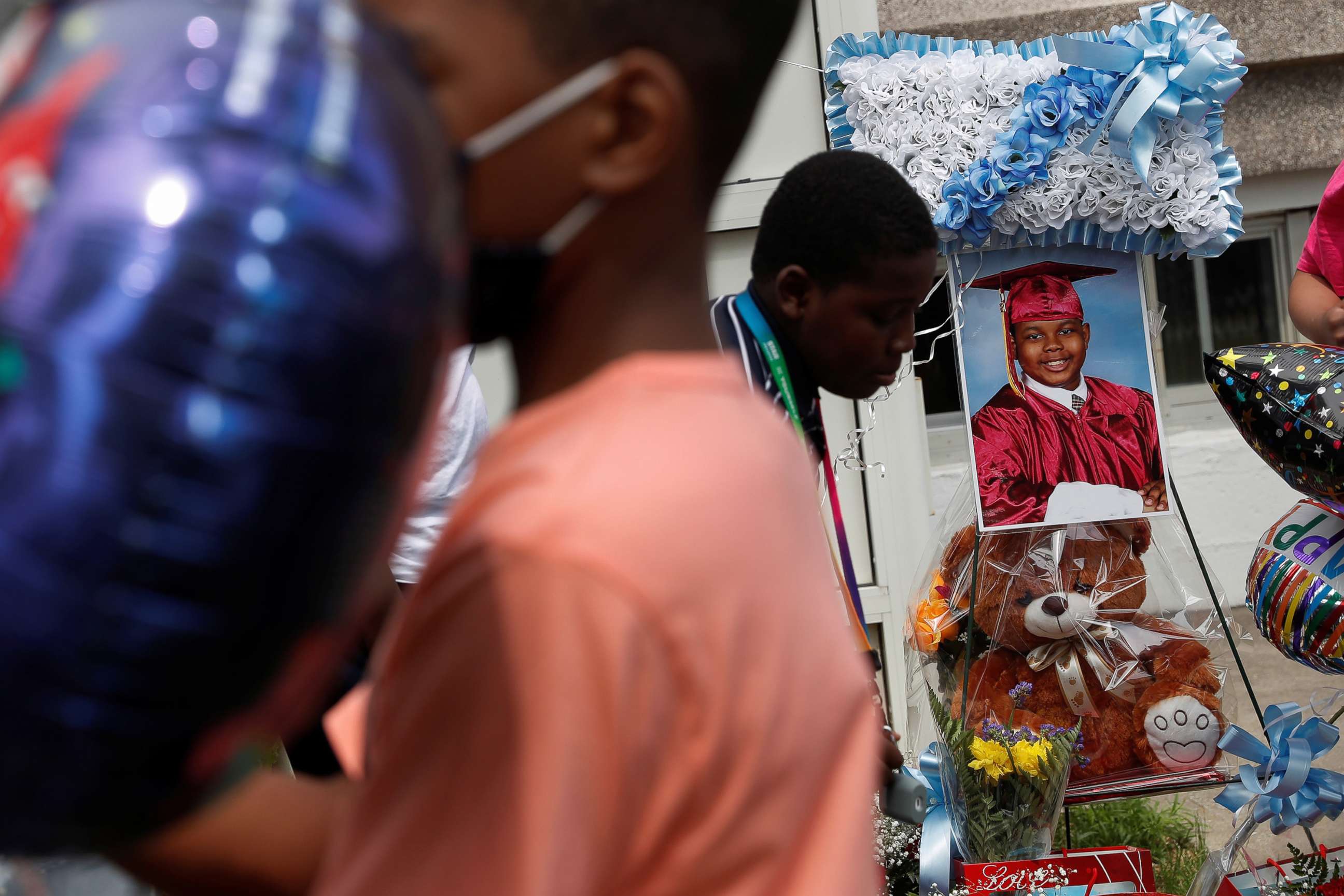 PHOTO: A photograph of 10-year-old Justin Wallace, who was shot and killed when a shooter fired rounds at a home in Queens, is displayed as students hang balloons outside the Challenge Preparatory Charter School in New York City, June 8, 2021.