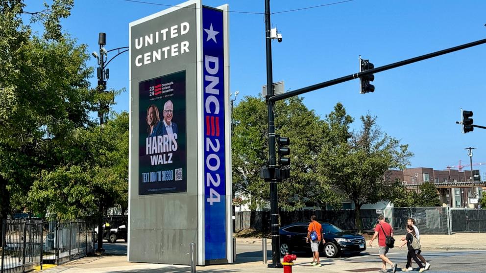 PHOTO: People walk by a Harris-Walz DNC sign near the United center in Chicago, Illinois, on August 13, 2024, prior to the Democratic National Convention. 