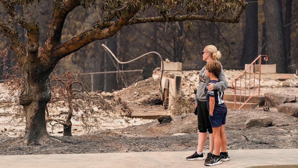 PHOTO: Jana Jensen surveys the neighborhood where her childhood home, owned by her parents, was lost to wildfire, while embracing her son, Aaren, 8, in Spokane, Washington, U.S., August 2, 2026.