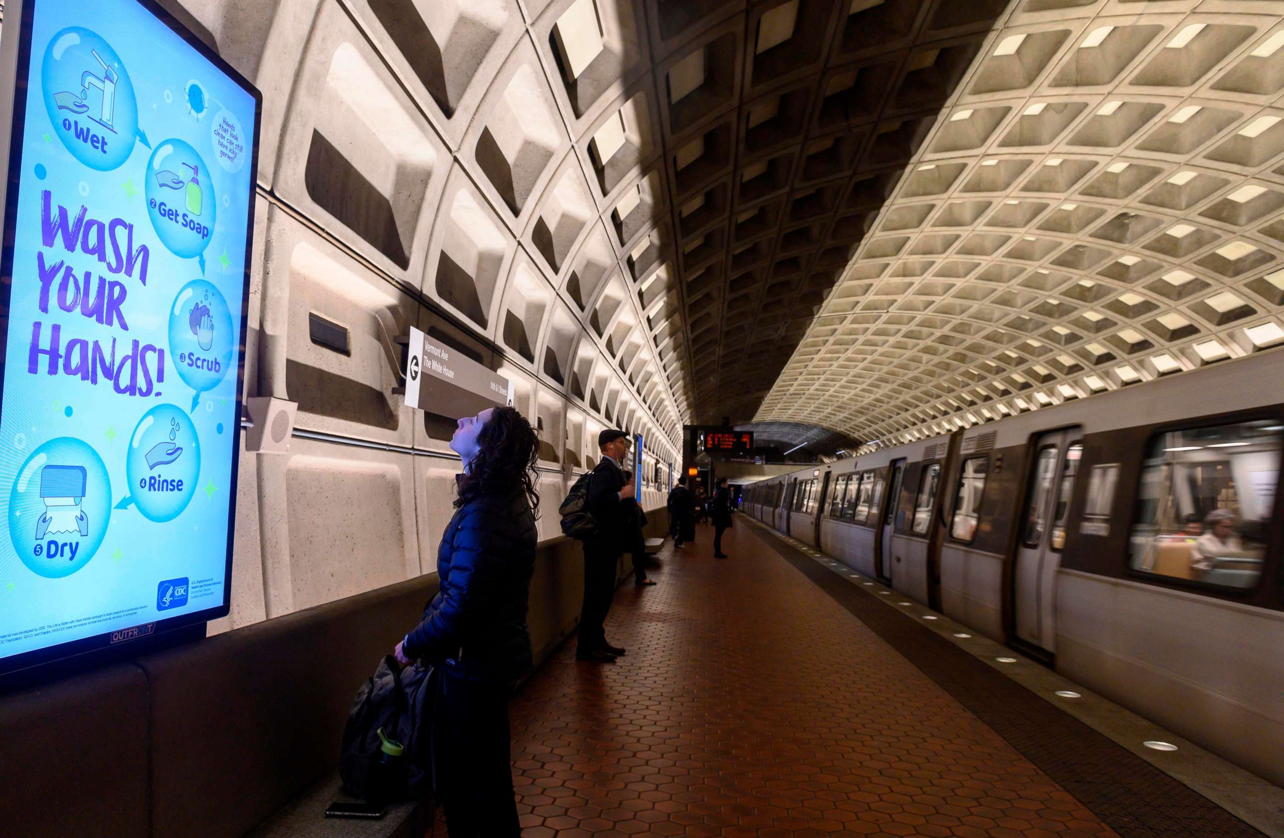 PHOTO: A woman reads a public awareness sign in response to the novel coronavirus outbreak, as she waits for a train in the Metro in Washington, D.C., on March 10, 2020. 