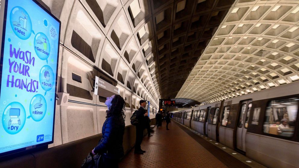 PHOTO: A woman reads a public awareness sign in response to the novel coronavirus outbreak, as she waits for a train in the Metro in Washington, D.C., on March 10, 2020. 