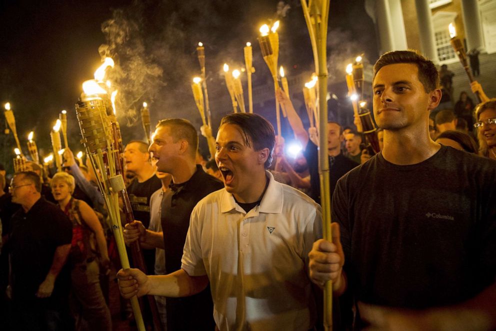 PHOTO: Torch-bearing protesters encircle and chant at counter protestors at the base of a statue of Thomas Jefferson after marching through the University of Virginia campus in Charlottesville, Va.,  Aug. 11, 2017. 