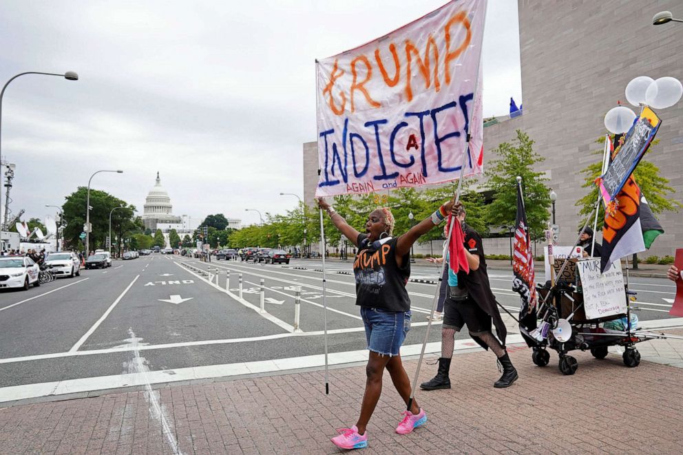 PHOTO: A demonstrator carries a banner, as people gather on the day former U.S. President Donald Trump, who is facing federal charges related to attempts to overturn his 2020 election defeat, appears at the U.S. District Court in Washington, Aug. 3, 2023.