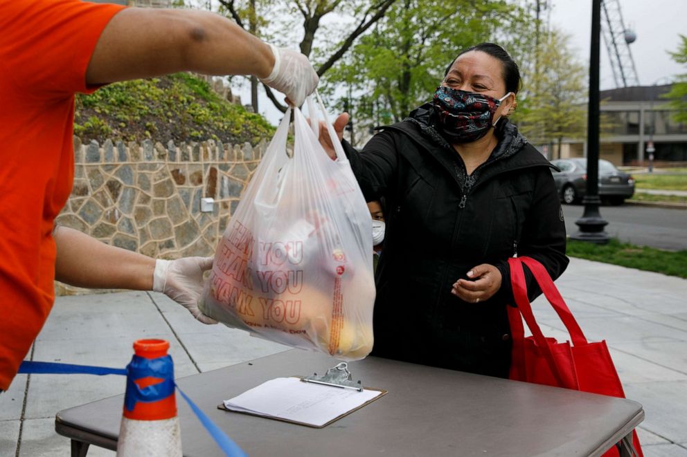 PHOTO: Janeth is handed a bag of donated food from a Methodist church, Tuesday, April 21, 2020, in Washington. She was pleased that the bag contained a bit of chicken and rice to cook. 