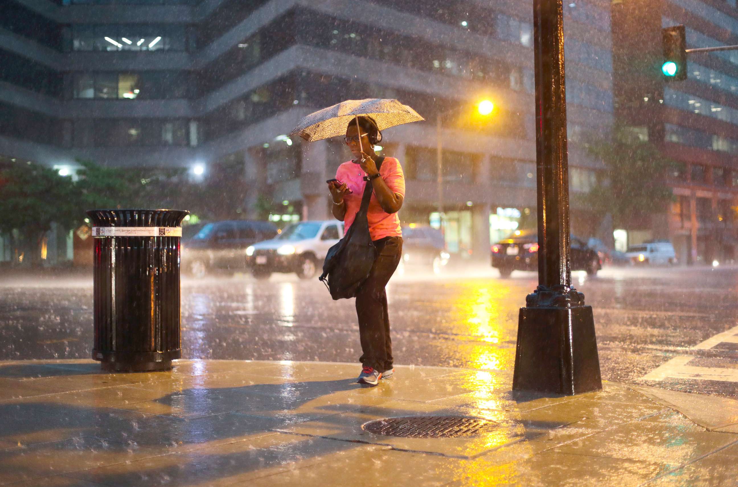 PHOTO: A woman checks her cell phone as she walks in the heavy rain showers in downtown Washington, May 14, 2018.