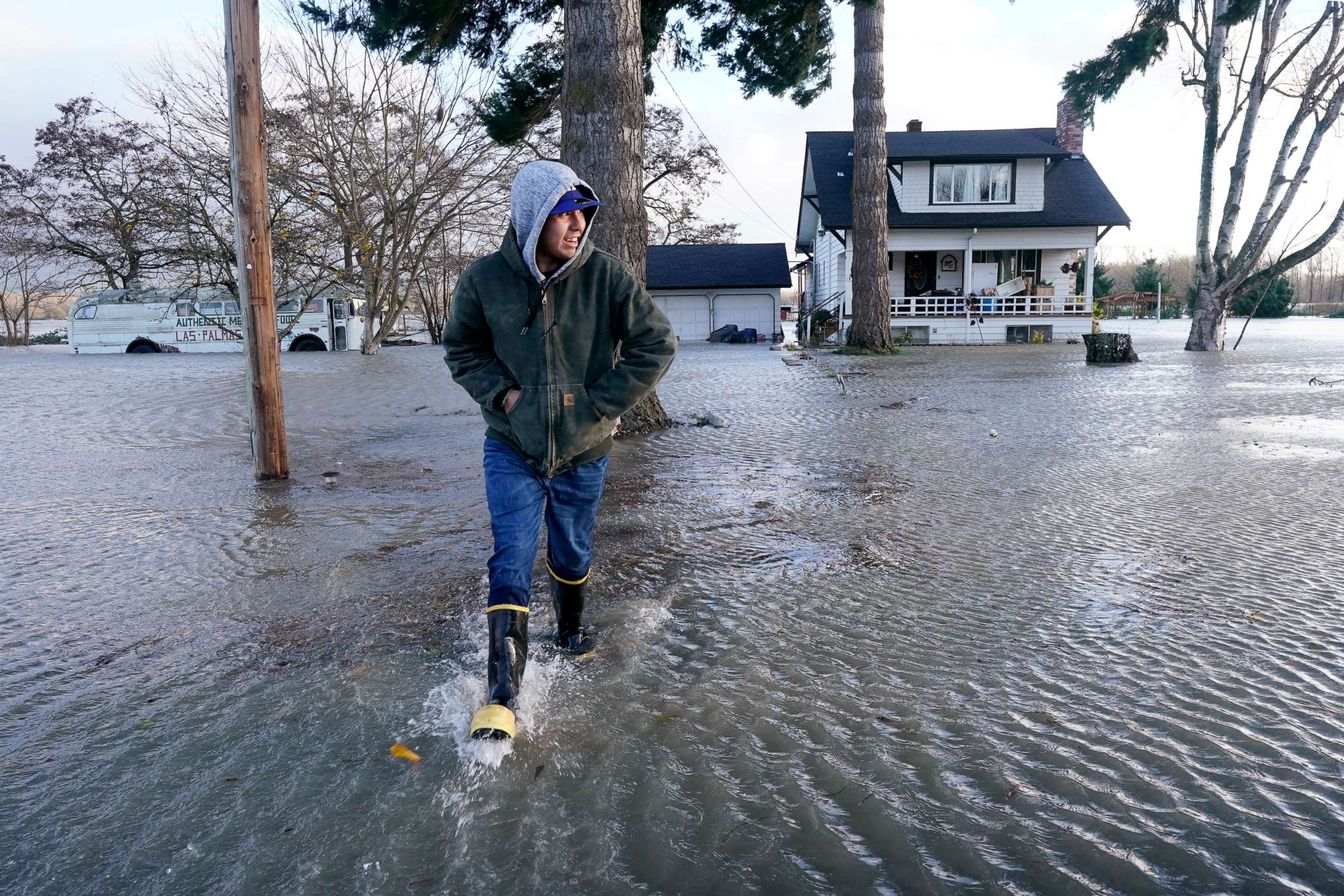 PHOTO: Benjamin Lopez steps from floodwater surrounding his parents home, Nov. 15, 2021, in Sedro-Woolley, Wash.