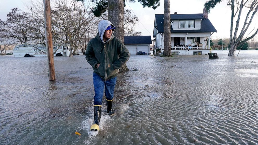PHOTO: Benjamin Lopez steps from floodwater surrounding his parents home, Nov. 15, 2021, in Sedro-Woolley, Wash.