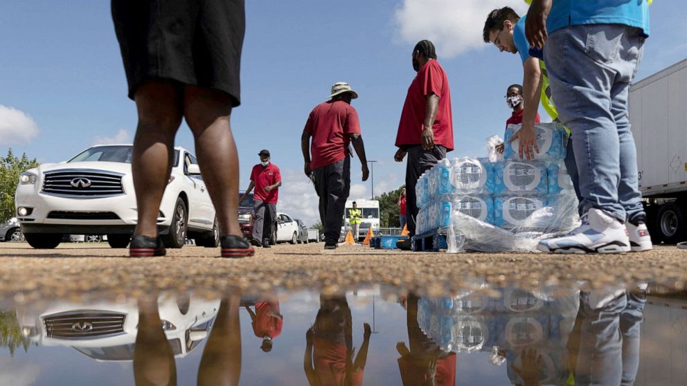 Volunteers help to carry bottles of water at a water distribution site in J...