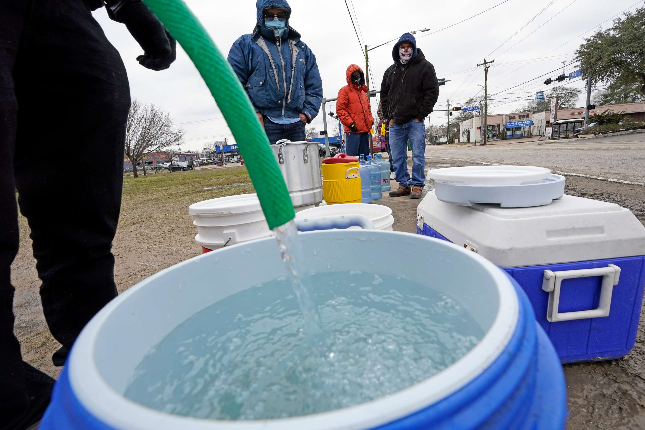PHOTO: A water bucket is filled as others wait in near freezing temperatures to use a hose from public park spigot, Feb. 18, 2021, in Houston.