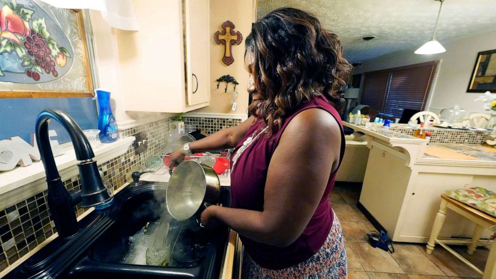 PHOTO: Bennie Hudson pours boiling water into her sink before washing dishes at her Jackson, Miss., Sept. 1, 2022.