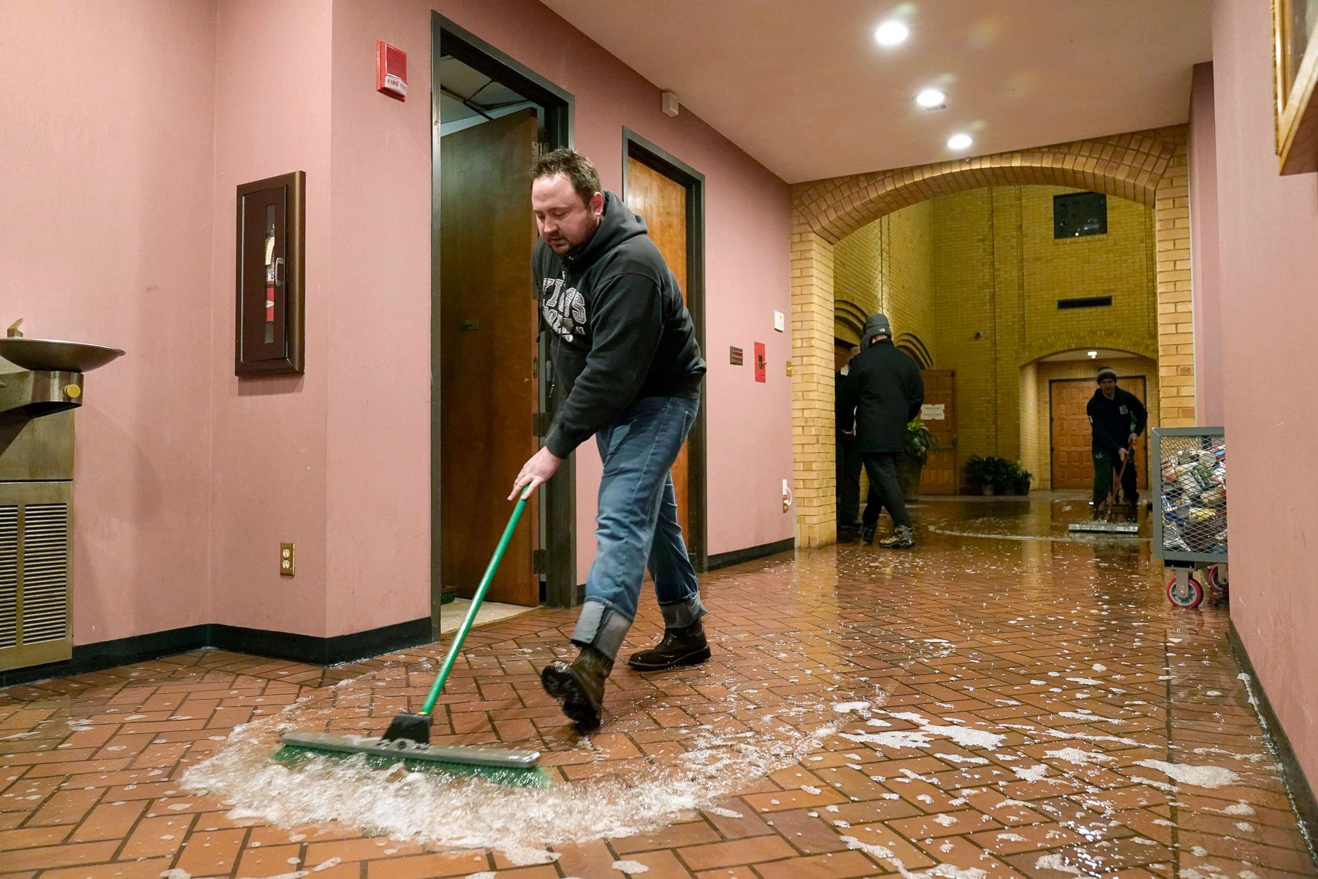 PHOTO: Father John Szatkowski of St. Paul The Apostle Church sweeps water from a broken water line out of his church in Richardson, Texas, Feb. 17, 2021, after a winter storm brought cold temperatures.