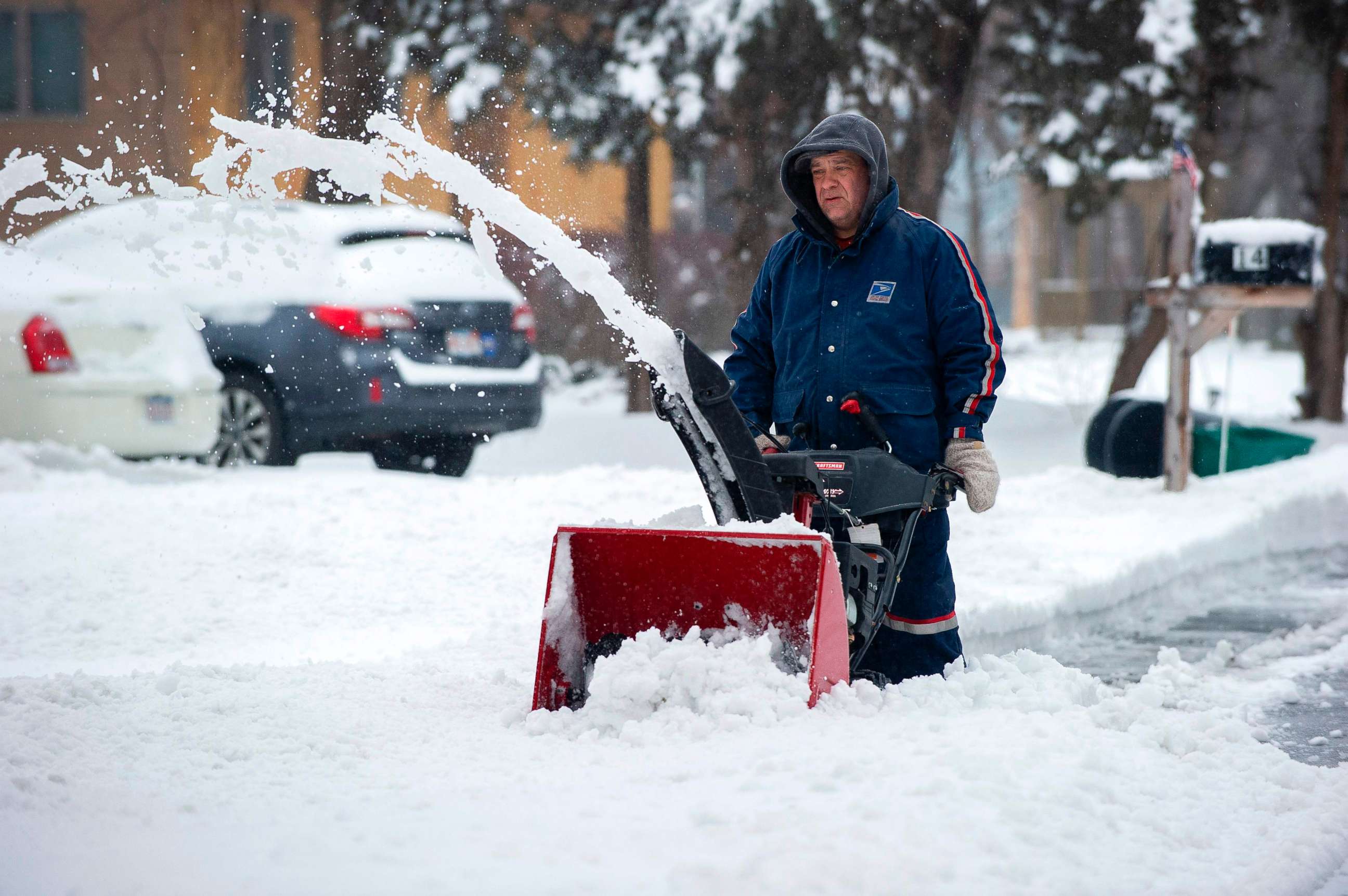PHOTO: A man in a US Postal Uniform uses a snow blower to clear a street during Winter Storm Harper in Saugus, Mass., Jan. 20, 2019.
