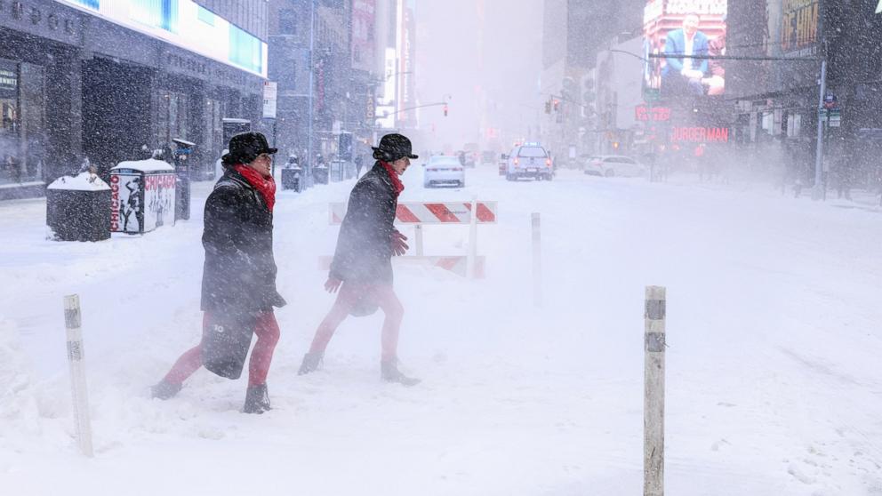 PHOTO: People walk across Sixth Avenue as snow falls in New York City on January 25, 2026.