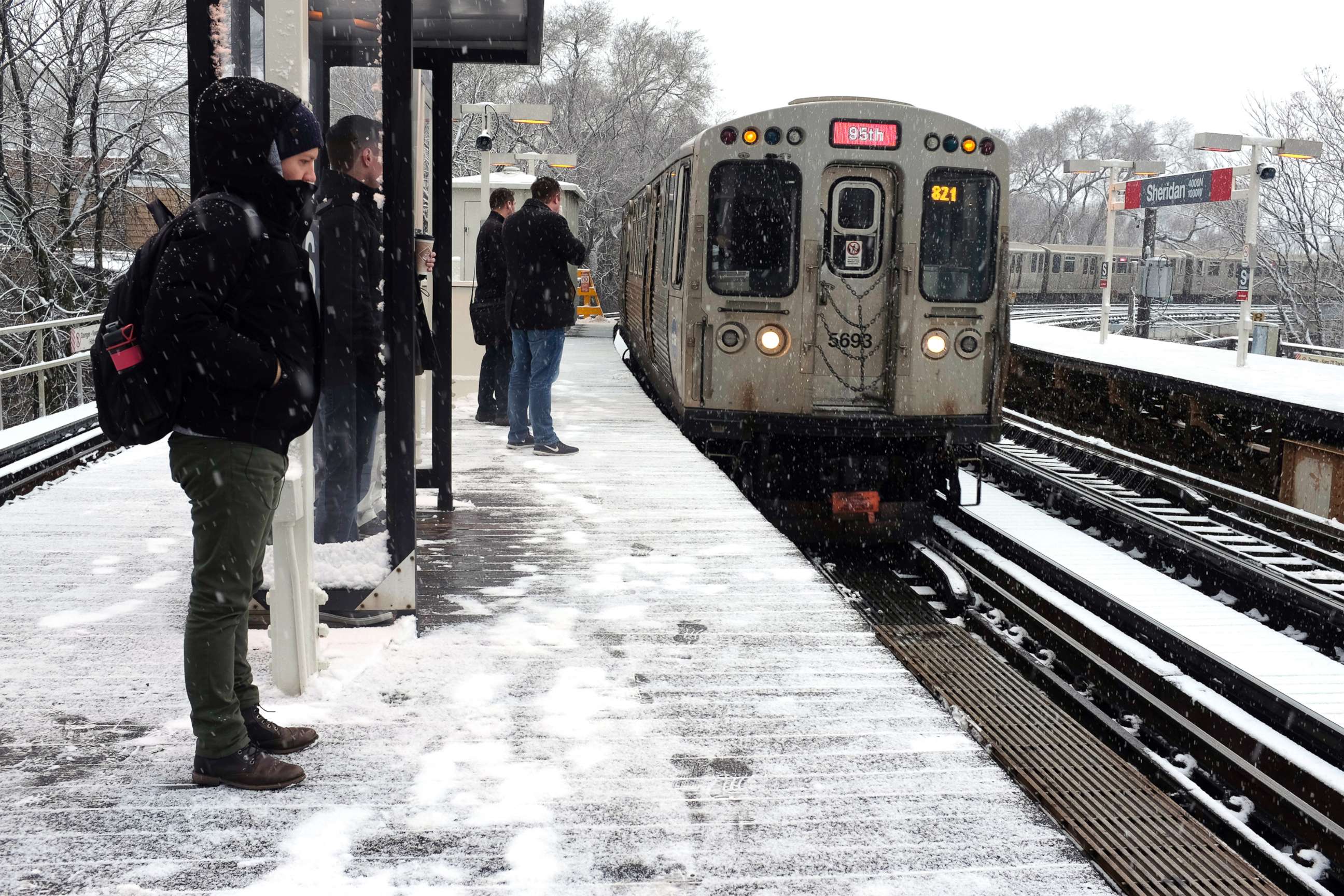 PHOTO: Snow falls as commuters wait for Chicago's El train on April 9, 2018, in Chicago.