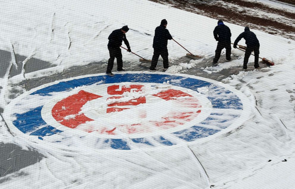 PHOTO: Workers at Wrigley Field clear snow before the Chicago Cubs home-opener baseball game against the Pittsburgh Pirates, in Chicago, on April 9, 2018. 