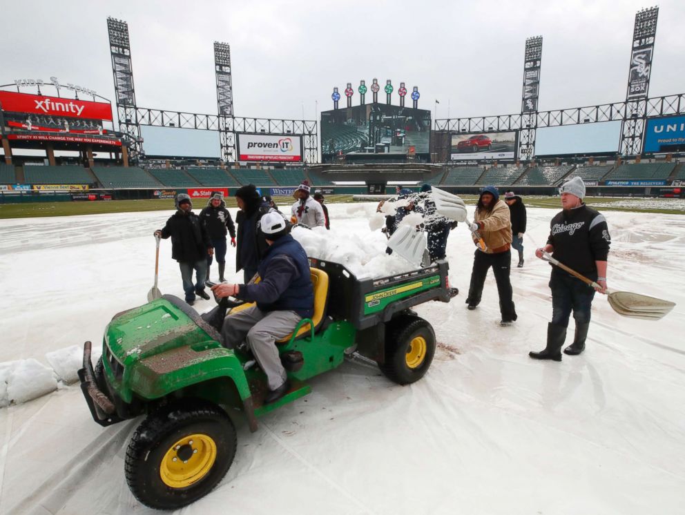 PHOTO: Grounds crew members remove snow from the field before a baseball game between the Chicago White Sox and the Tampa Bay Rays in Chicago on April 9, 2018.