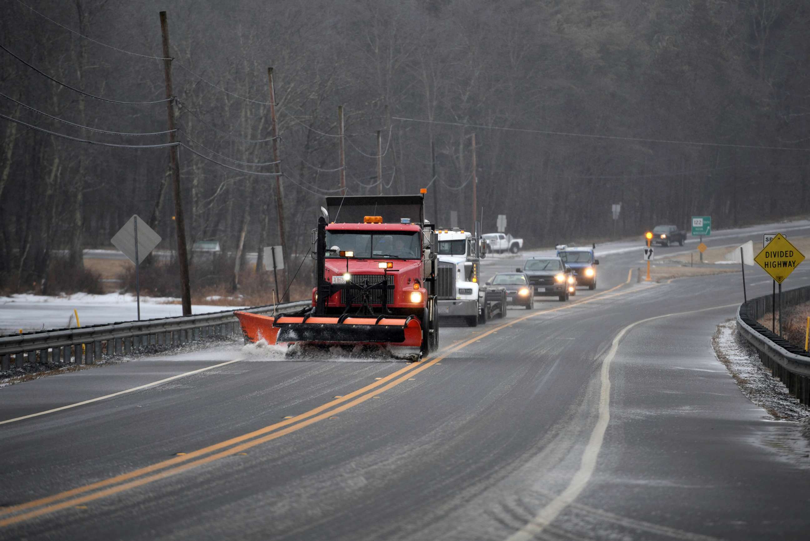 PHOTO: A plow and salter leads cars in the inclement weather, in Rutland, Mass., Dec. 30, 2019. A combination of freezing rain and snow has hit parts of northern New England.