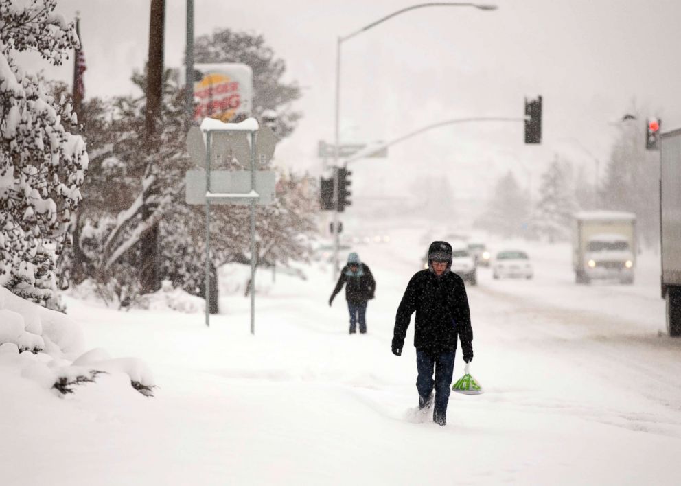 PHOTO: Northern Arizona University student Matthew Bartush, right, carries breakfast through the snow as it falls over Flagstaff, Ariz., Feb. 21, 2019.