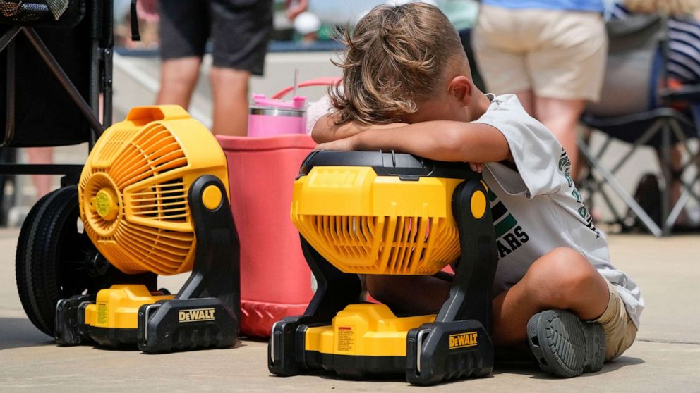 PHOTO: Braxton Hicks, 7, of Livingston, Texas, holds his face to a portable fan to cool off during the DYB, formerly Dixie Youth Baseball, Little League tournament in Ruston, La., Aug. 9, 2023.