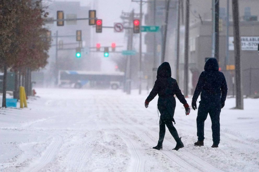 PHOTO: People walk down a street during a winter storm in Oklahoma City, Feb. 14, 2021. Snow and ice blanketed large swaths of the U.S prompting canceled flights, making driving perilous and reaching into areas as far south as Texas's Gulf Coast.
