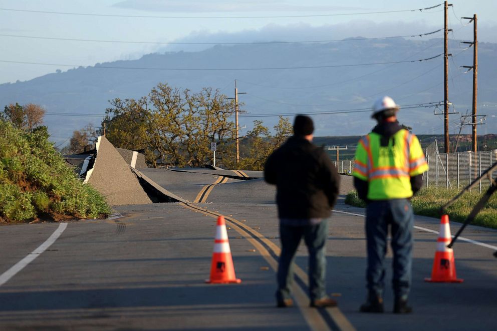 PHOTO: A Pacific Gas and Electric (PG&E) worker looks at a road that buckled when it was undermined by a mudslide during a Bomb Cyclone storm earlier in the week on March 23, 2023 in Novato, Calif.