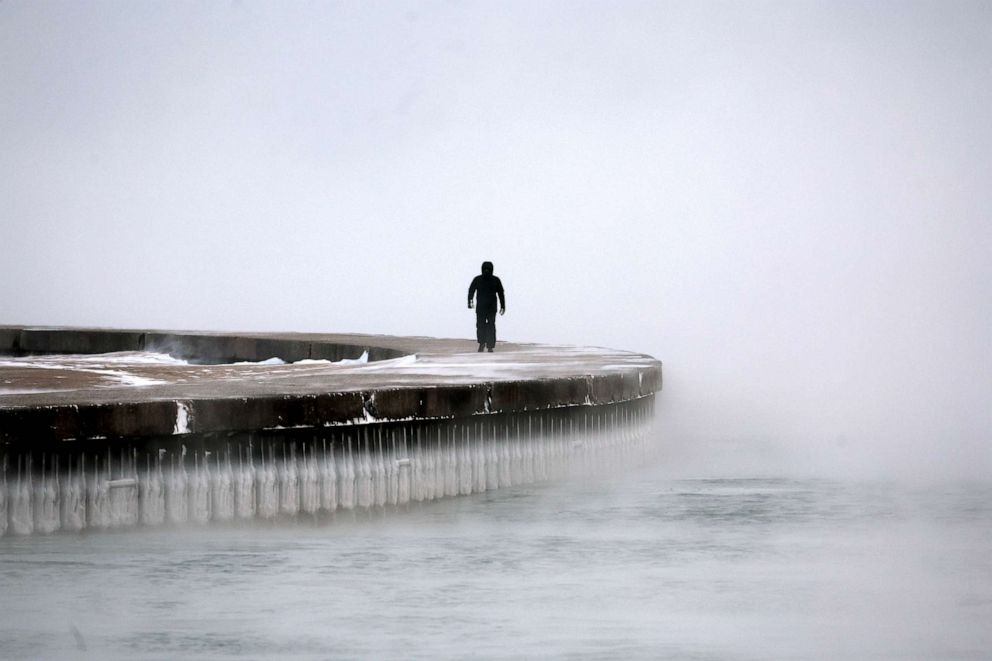 PHOTO: A man walks along Lake Michigan at sunrise as temperatures hover about -6 degrees, Dec. 22, 2022 in Chicago.