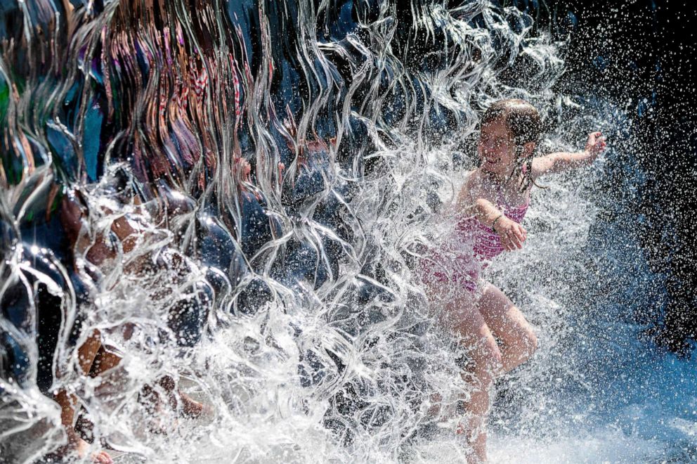 PHOTO: A young girl splashes through a waterfall at a park in Washington, D.C., June 28, 2021.