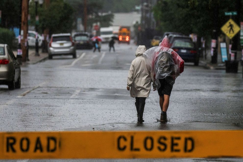 PHOTO: People walk along a closed road for floods as Tropical Storm Elsa passes through Hoboken, N.J., July 9, 2021.