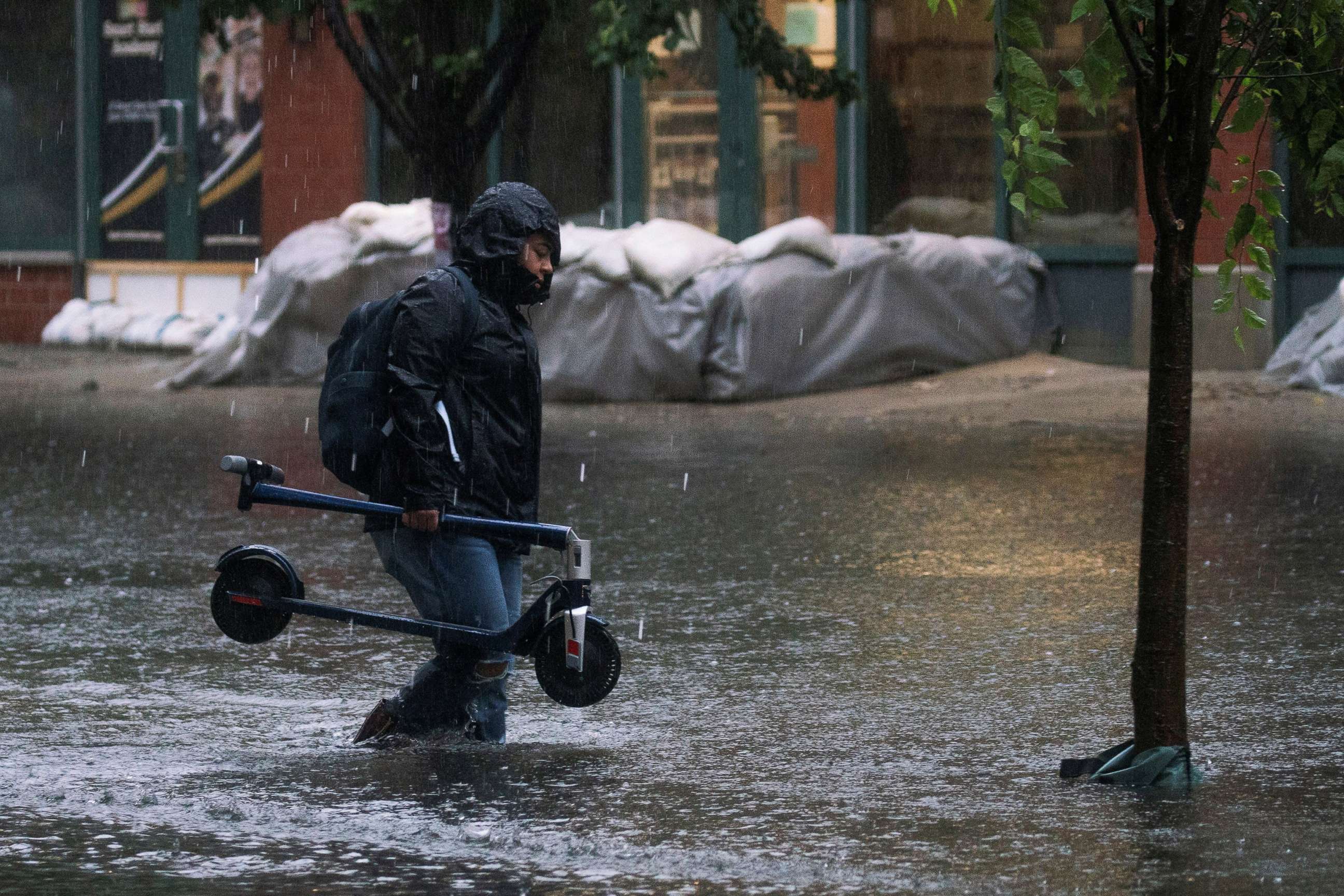 PHOTO: A woman makes her way on a flooded street as Tropical Storm Elsa passes through Hoboken, N.J., July 9, 2021.