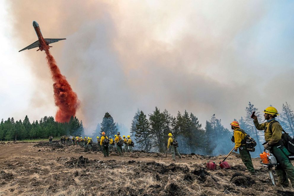 PHOTO: Wildland firefighters watch and take video with their cellphones as a plane drops fire retardant on Harlow Ridge above the Lick Creek Fire, southwest of Asotin, Wash., July 12, 2021.