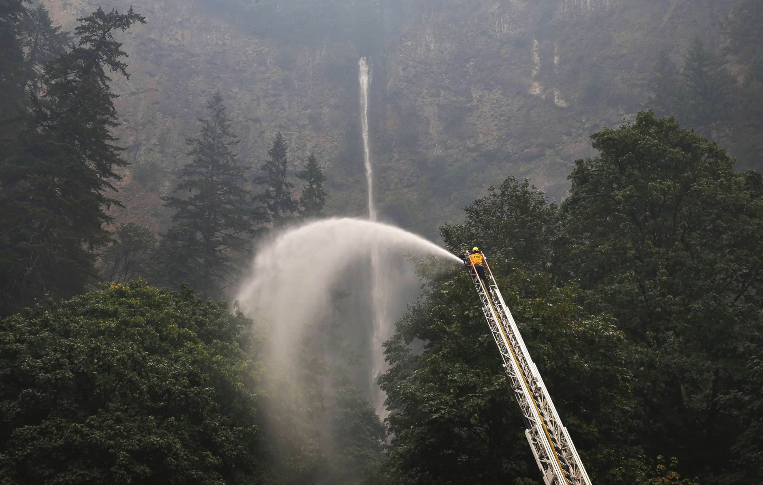 PHOTO: A firefighter sprays water on the trees around Multnomah Falls, Sept. 6, 2017, as the Eagle Creek Fire continues to burn east of Troutdale, Ore. 