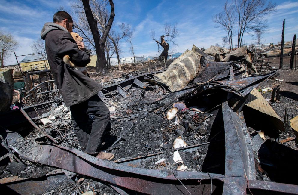 PHOTO: Savino Sanchez holds his mother-in-law's dog as he and his family search through the remains of their home in Monte Vista, Colo., Friday, April 22, 2022