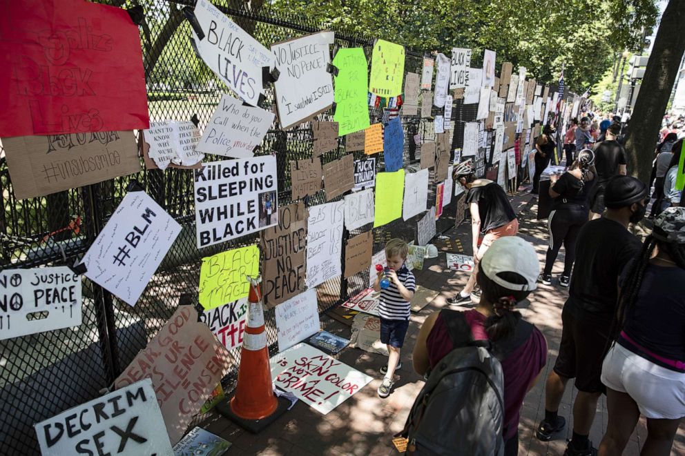 PHOTO: People read signs left by protestors on the fence erected preventing them from getting into Lafayette Park across the street from the White House during protests over the death of George Floyd, June 7, 2020, in Washington, D.C.