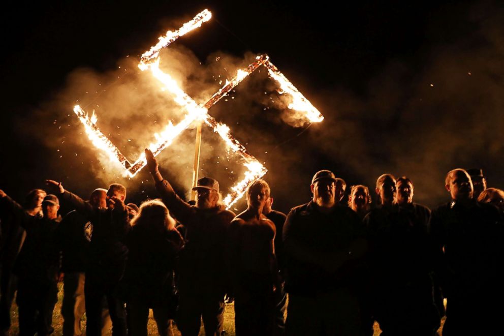 PHOTO: Members  of the National Socialist Movement, one of the largest neo-Nazi groups in the US, hold a swastika burning after a rally, April 21, 2018, in Draketown, Ga. 