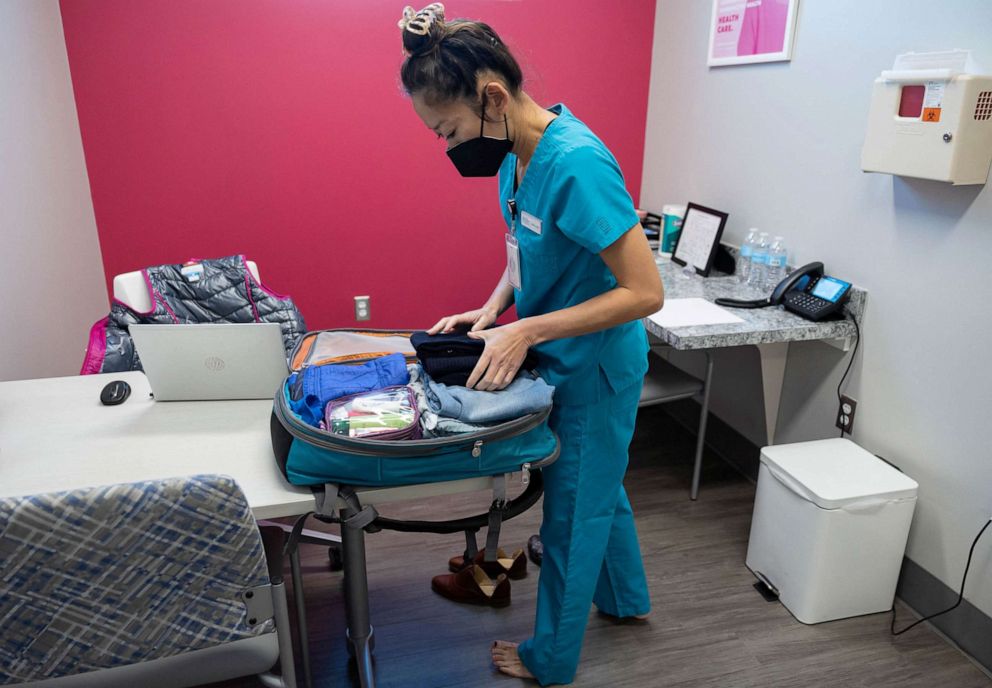PHOTO: Dr. Shelly Tien, 40, changes into scrubs and puts her clothes in her backpack in her office at Planned Parenthood in Birmingham, Alabama, March 14, 2022.