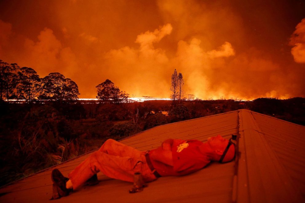 PHOTO: Mark Clawson, 64, rests while watching a lava flow from a neighbor's roof on the outskirts of Pahoa during ongoing eruptions of the Kilauea Volcano in Hawaii, June 6, 2018.