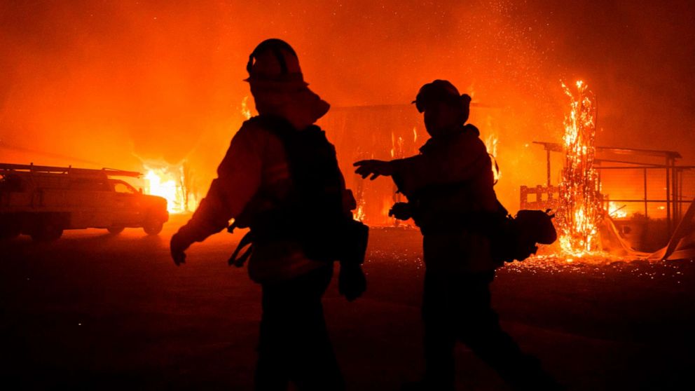 PHOTO: Firefighters give direction as a wind-driven fire burns a structure on a farm during the Kincade fire in Windsor, Calif., Oct. 27, 2019.