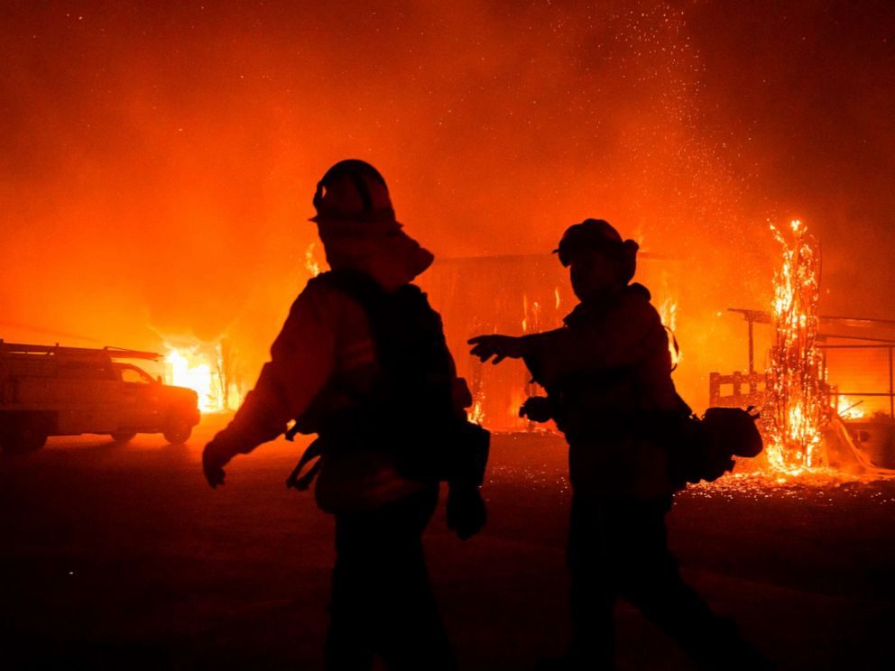 PHOTO: Firefighters give direction as a wind-driven fire burns a structure on a farm during the Kincade fire in Windsor, Calif., Oct. 27, 2019.