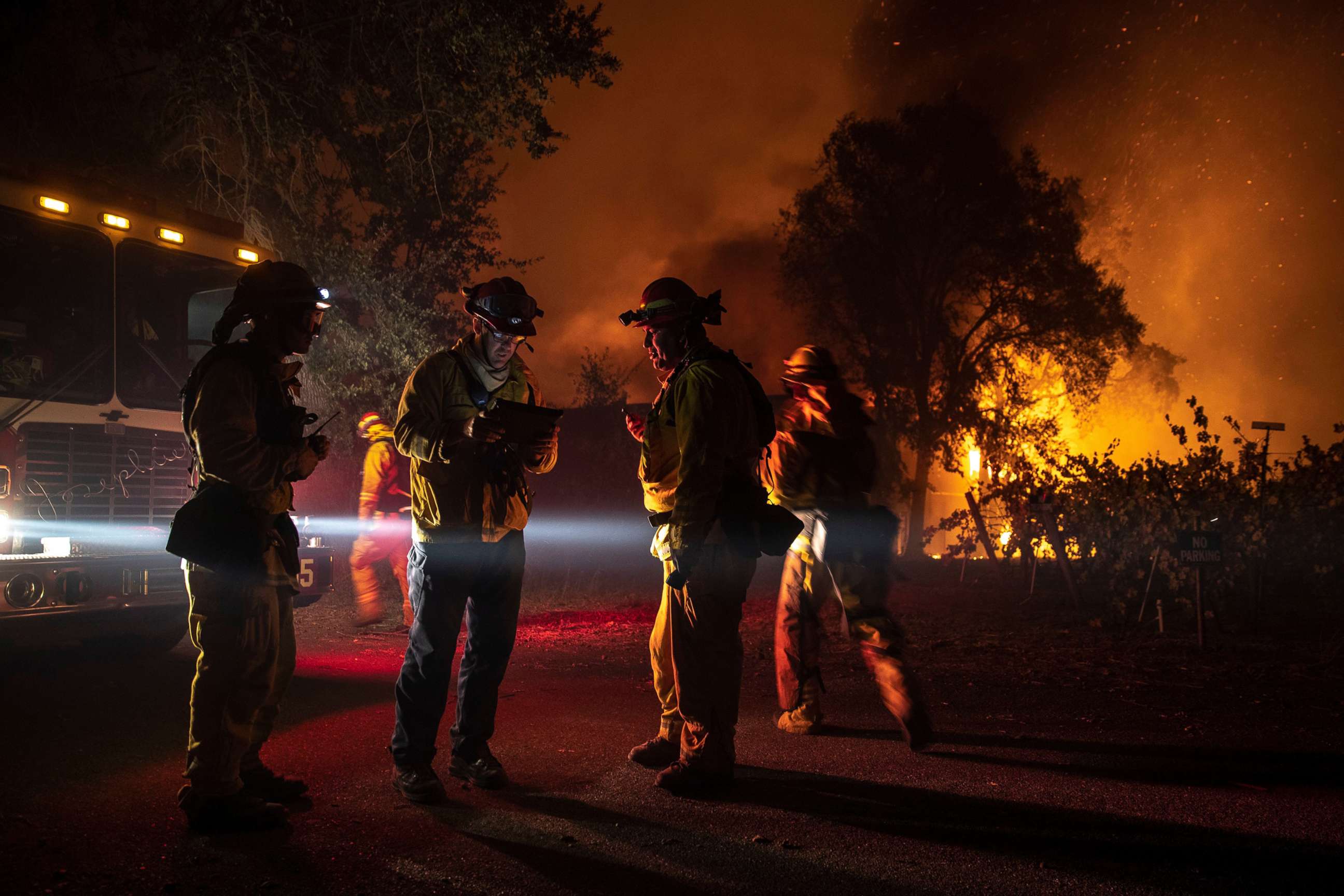 PHOTO: Firefighters plan their move as a building burns out of control, as the Kincade Fire continues to burn in Healdsburg, Calif., Oct. 27, 2019.