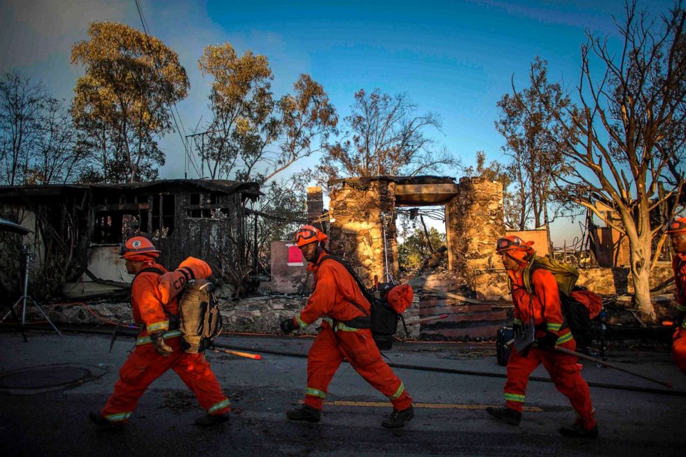 PHOTO: Firefighters walk past a burnt home during the Getty Fire in Brentwood, Calif., Oct. 28, 2019.