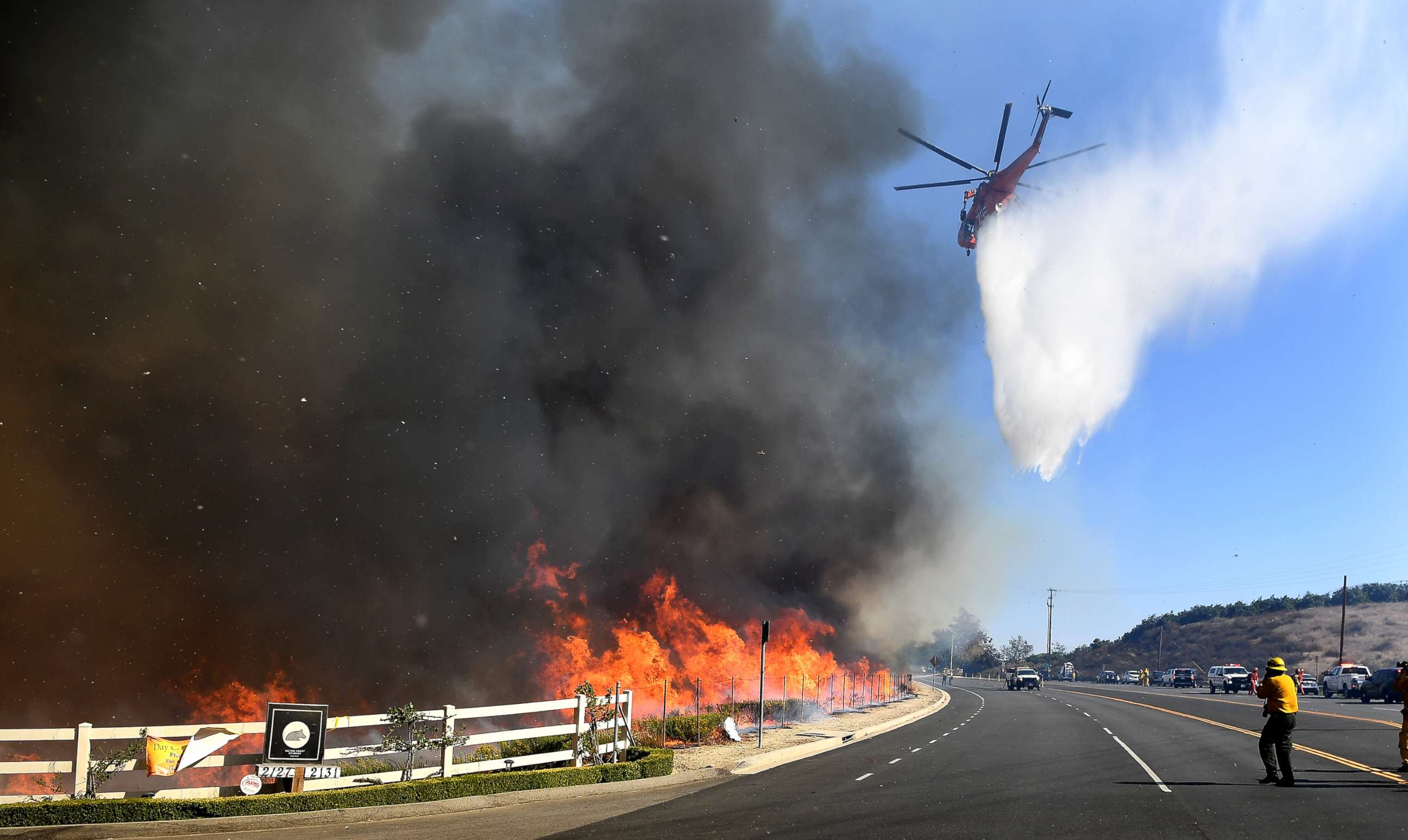 PHOTO: A water-dropping helicopter passes makes a drop along Madera Road as the Easy Fire burns in Simi Valley, Calif., Oct. 30, 2019.