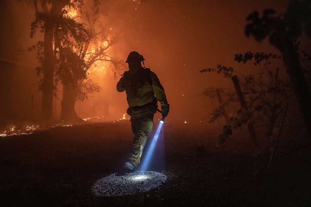 PHOTO: A firefighter walks past a building burning out of control, as the Kincade Fire continues to burn in Healdsburg, Calif., 27 Oct. 27, 2019. 