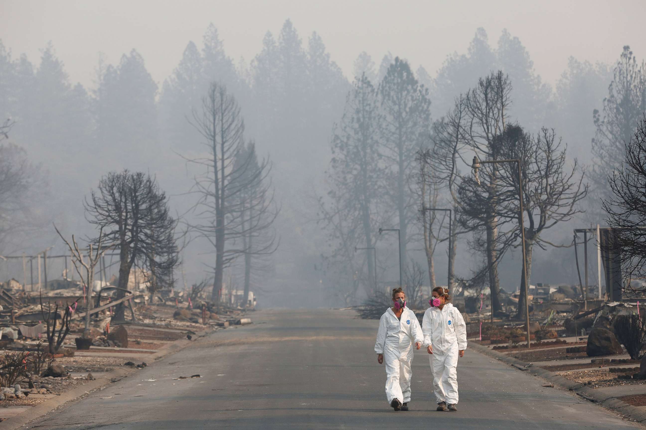 PHOTO: Forensic anthropologists Kyra Stull (L) and Tatiana Vlemincq walk through a trailer park destroyed by the Camp Fire in Paradise, Calif., Nov. 17, 2018.  