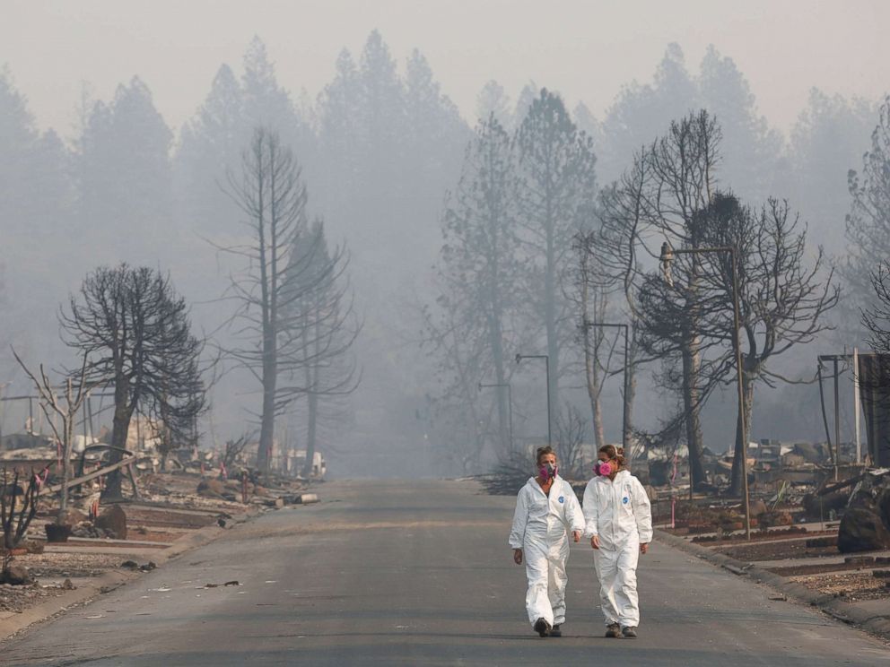 PHOTO: Forensic anthropologists Kyra Stull (L) and Tatiana Vlemincq walk through a trailer park destroyed by the Camp Fire in Paradise, Calif., Nov. 17, 2018.