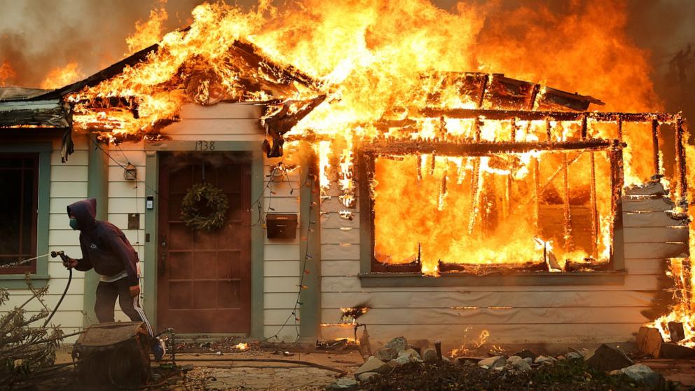 PHOTO: A person uses a garden hose in an effort to save a neighboring home from catching fire during the Eaton Fire, Jan. 8, 2025, in Altadena, California. 