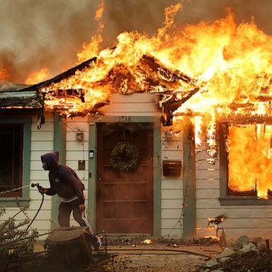 PHOTO: A person uses a garden hose in an effort to save a neighboring home from catching fire during the Eaton Fire, Jan. 8, 2025, in Altadena, California. 